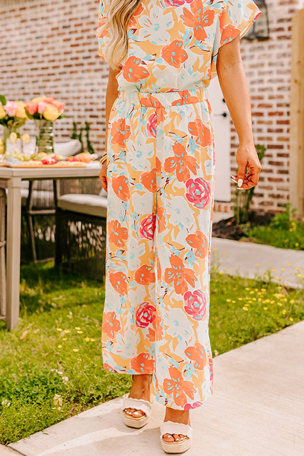 Orangefarbenes Set mit Bluse und Hose mit weitem Bein und kräftigem Blumenmuster