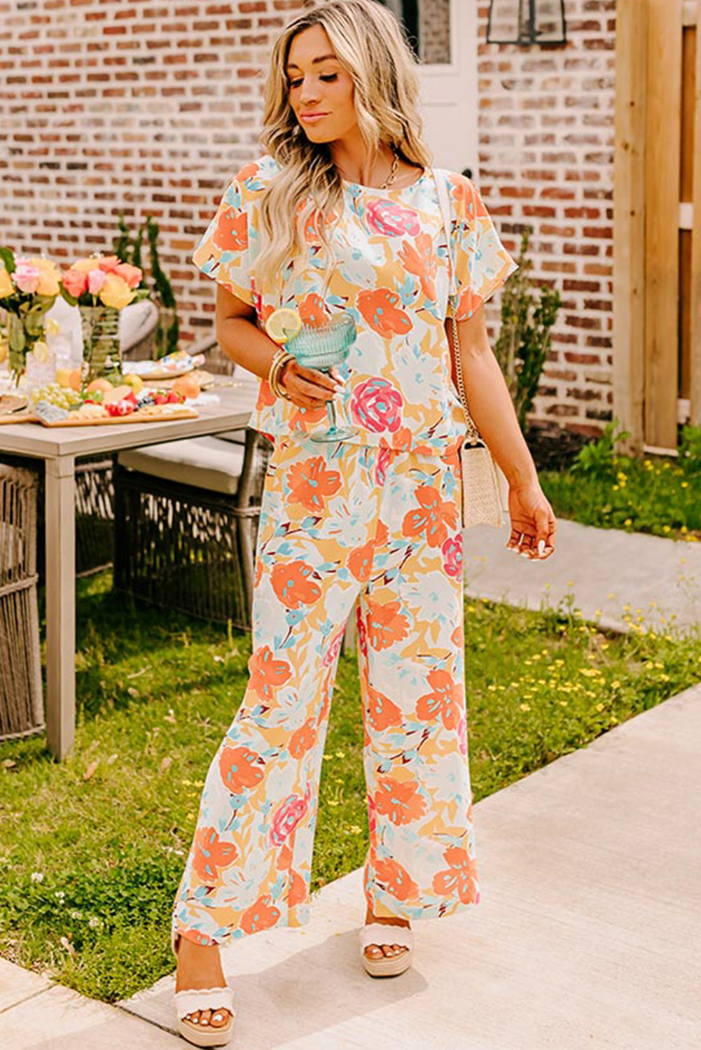 Orangefarbenes Set mit Bluse und Hose mit weitem Bein und kräftigem Blumenmuster